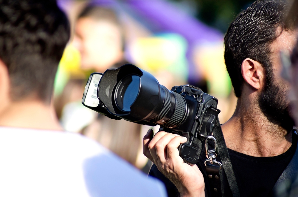 hand of a photographer holding a dslr camera with a flash