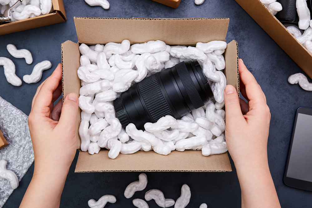 hands unpacking parcel with camera lens inside