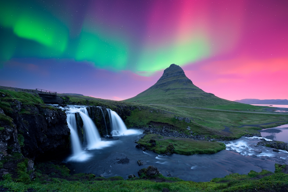 Kirkjufellsfoss waterfall and Kirkjufell volcano under Northern lights Iceland