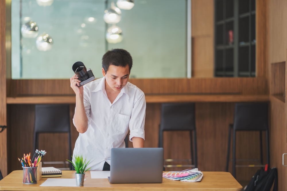 man holding a camera and using laptop