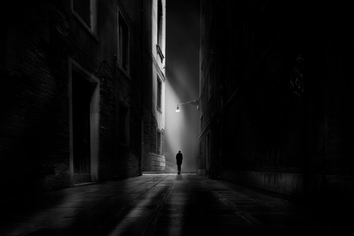 Man walking alone under a streetlight at night