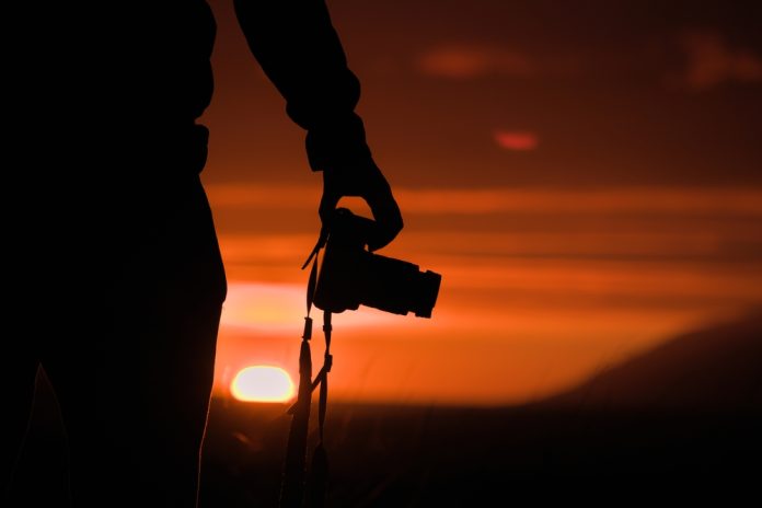 photographer holding camera at sunset
