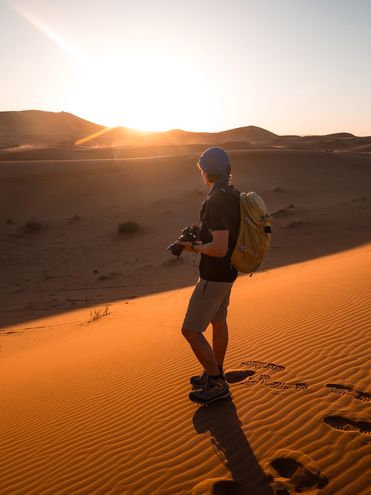 Photographer standing on erg chebbi sand dunes in sahara desert