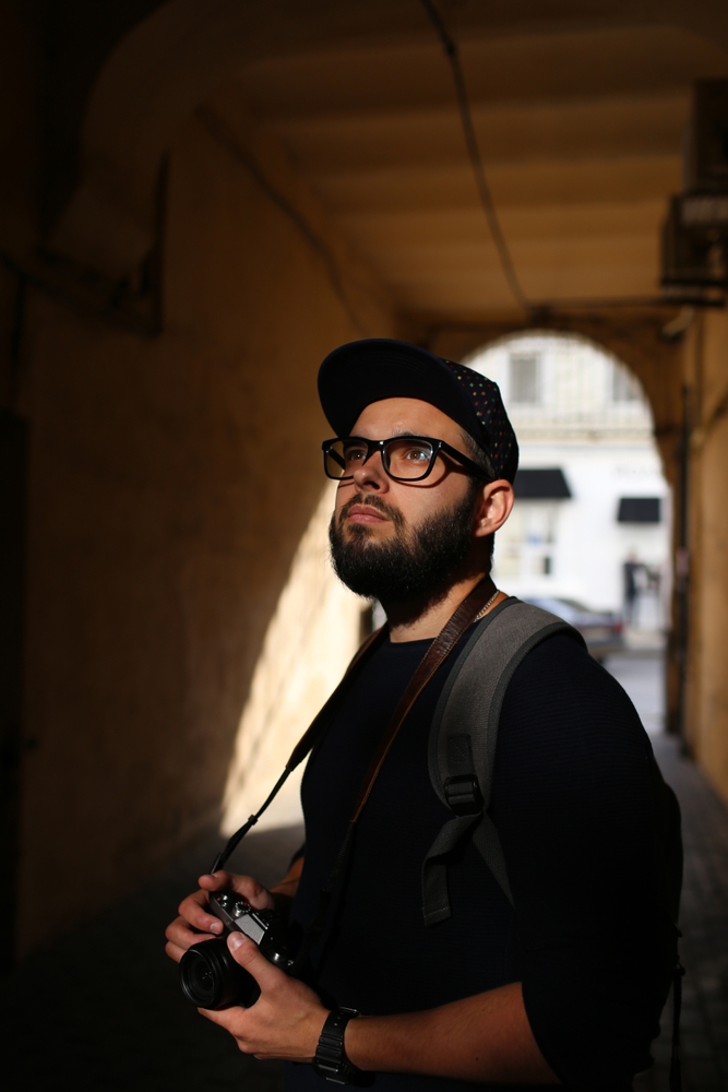photographer with a beard in glasses and a cap with a vintage camera