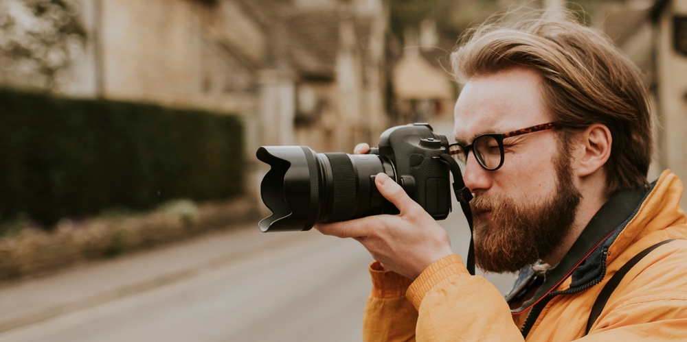 photographer with beard and glasses taking a photo with a DSLR camera