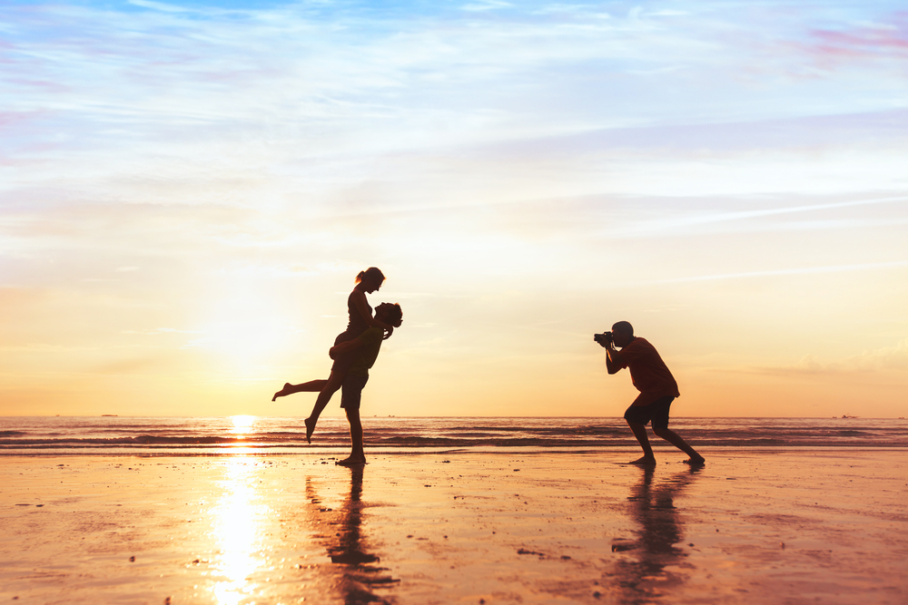 photographer working with a couple on the beach