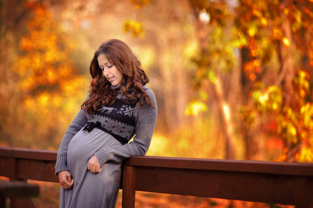Pregnant woman in front of fall foliage