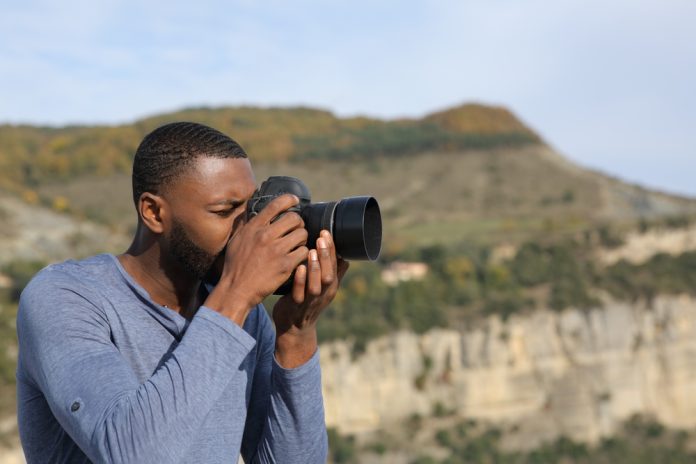 side view of a man using a dslr camera in the mountains