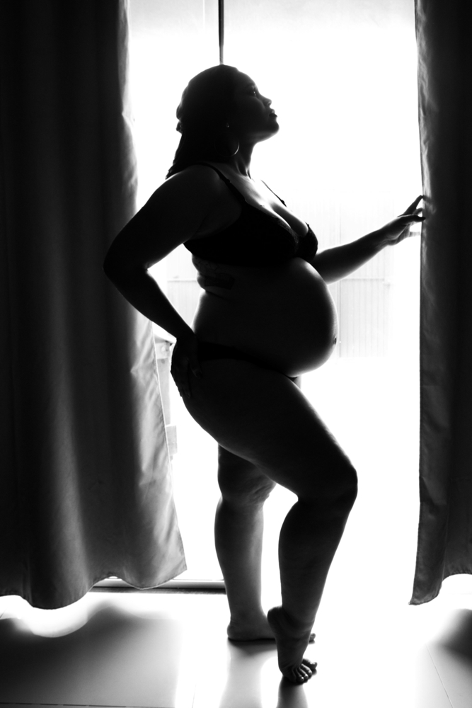 Silhouette of a pregnant woman by a window BW