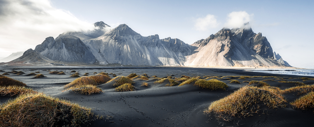Stokksnes cape and Vestrahorn Mountain with black sand and grass in the foreground